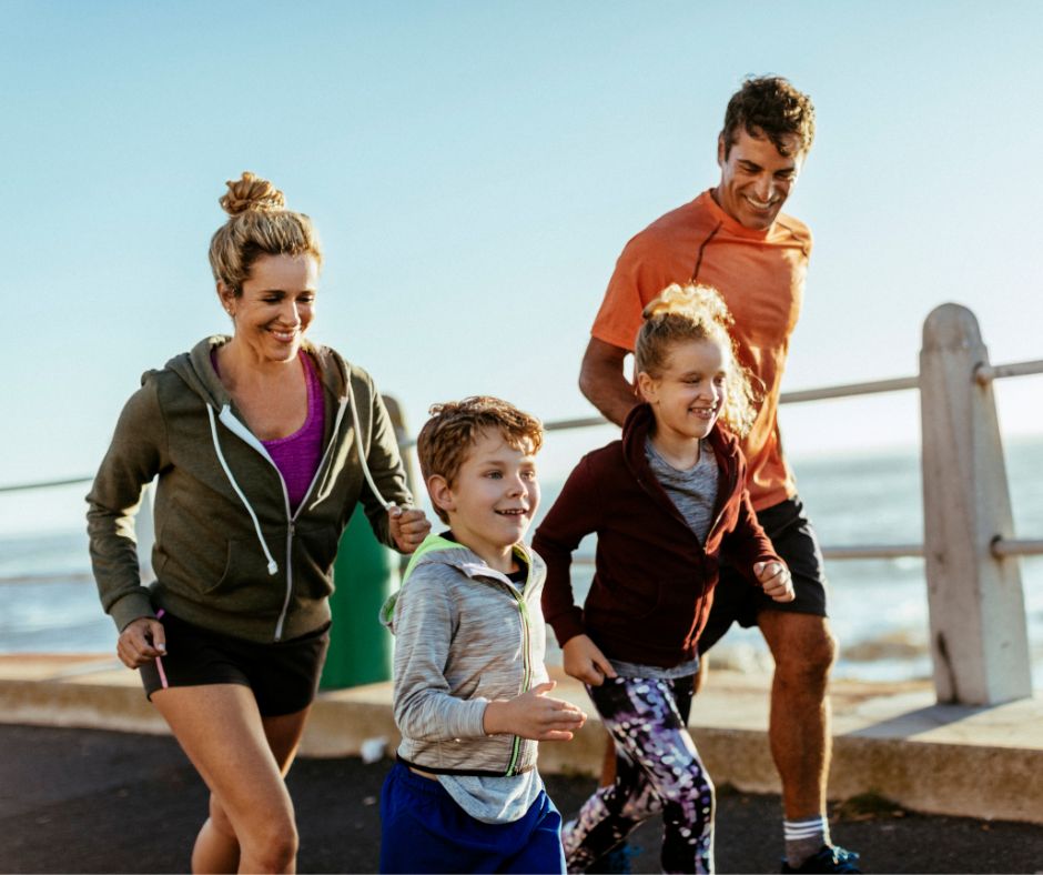 Family running on path by San Diego beach